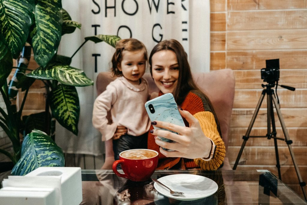 Blogger mother and her little daughter have fun together with the vlog camera. Young parenting