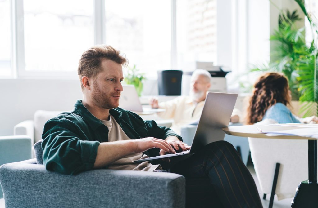 Caucasian male graphic designer using laptop computer for creating website for startup project